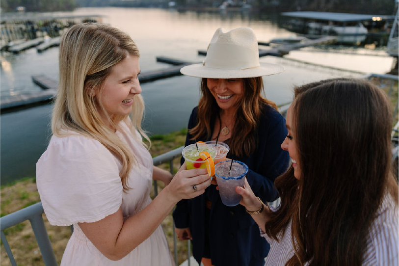 Friends toasting cocktails at golden hour by the marina